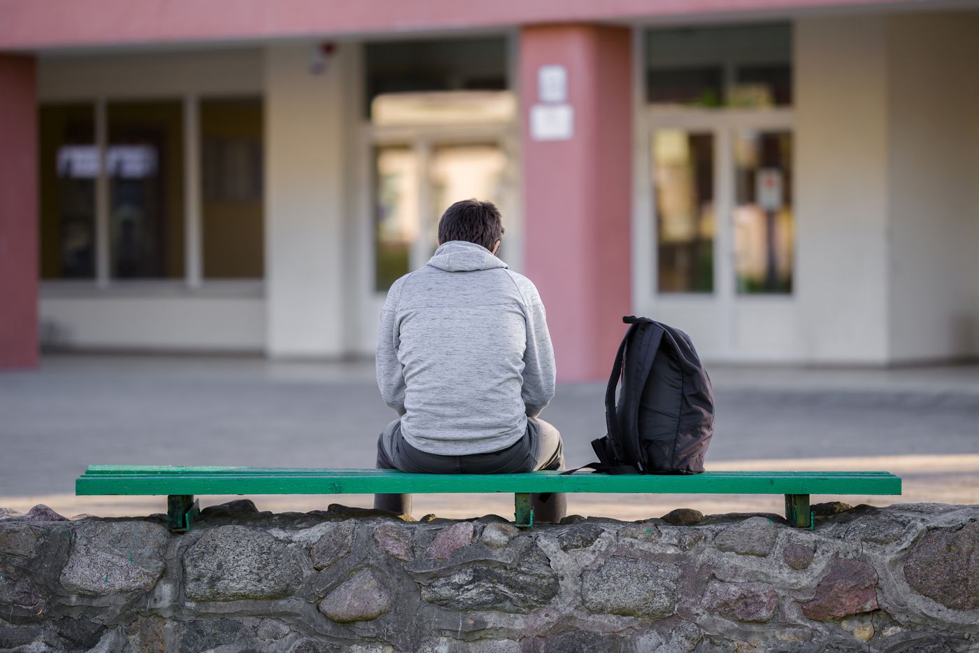 A person sitting alone on a bench outside a facility